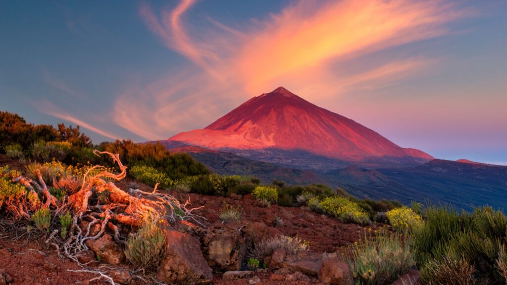 Senderista alcanzando el cráter del Teide con nubes bajas y terreno de lava volcánica.