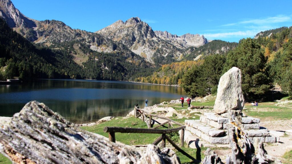 Senderista cruzando un collado de bloques de granito con vistas a los lagos de Aigüestortes.