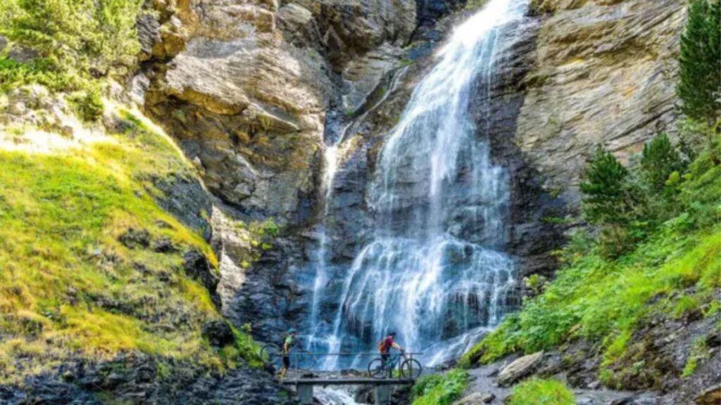 Senderista cruzando el puente frente a la gran Cascada del Bom en el Valle de Benasque.