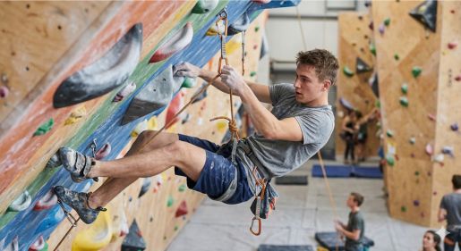 Escalador practicando técnica para como chapar eficientemente en un plafón de entrenamiento.
