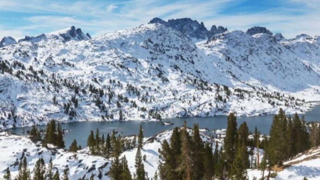 Vista panorámica de una laguna glaciar rodeada de picos nevados en la Integral de Sierra Nevada.