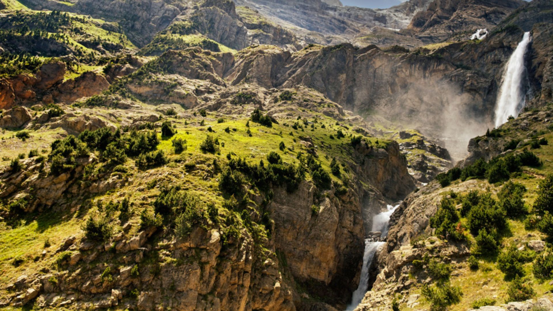 Infografía panorámica de la GR11 Transpirenaica mostrando la transición técnica entre el Circo de Bujaruelo con cascadas y el Ibón de Tebarray con nieve residual y pinares alpinos.
